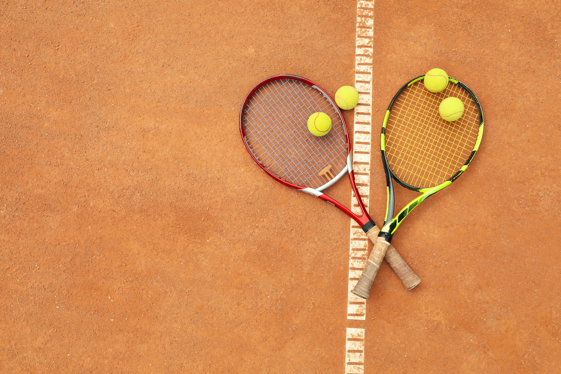 tennis racquets with tennis balls on clay court